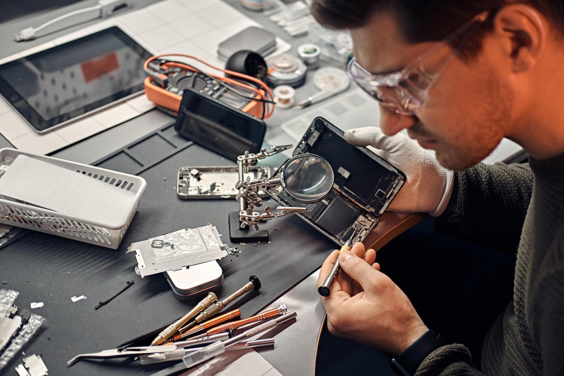 technician repairing smartphone under magnifier
